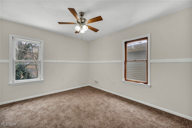 carpeted spare room with visible vents, a ceiling fan, and baseboards