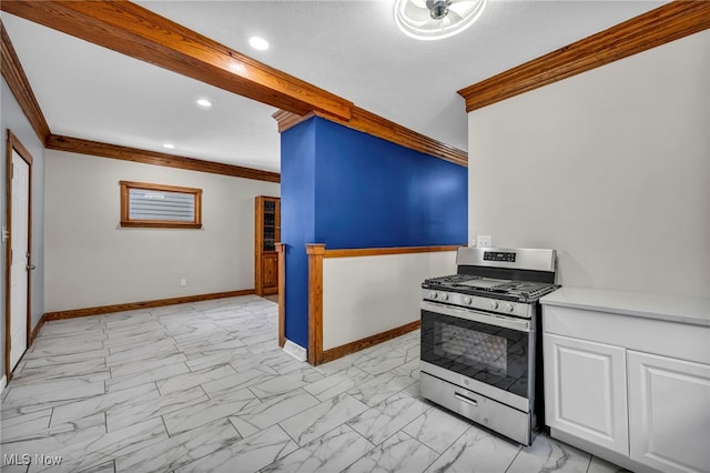 kitchen featuring marble finish floor, ornamental molding, white cabinets, stainless steel gas range oven, and baseboards