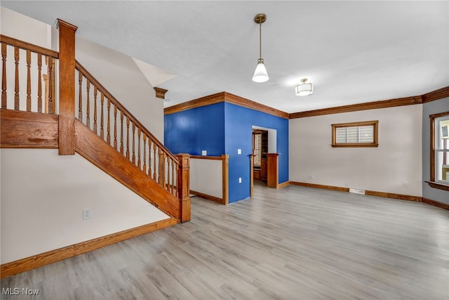 unfurnished living room featuring crown molding, visible vents, wood finished floors, baseboards, and stairs