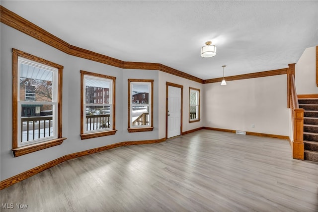 unfurnished living room featuring light wood-style floors, stairs, baseboards, and ornamental molding