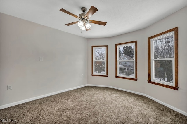 spare room featuring carpet floors, a ceiling fan, and baseboards