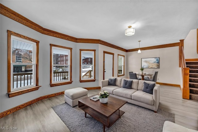 living area featuring light wood-style flooring, stairs, ornamental molding, and a wealth of natural light