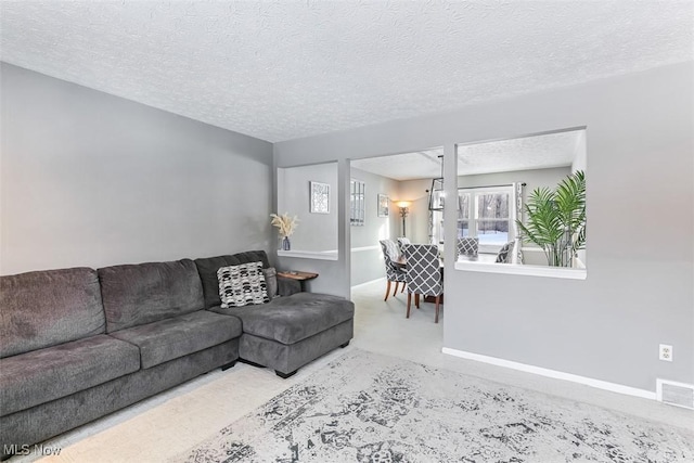 living area featuring visible vents, a textured ceiling, and baseboards