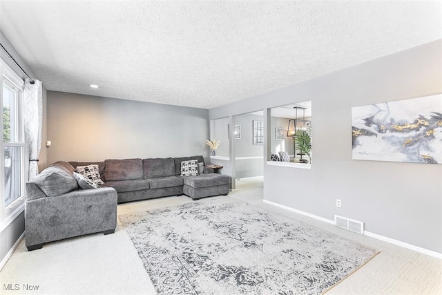 carpeted living room with visible vents, baseboards, and a textured ceiling