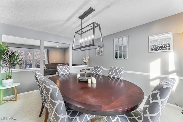 carpeted dining area with a textured ceiling and baseboards