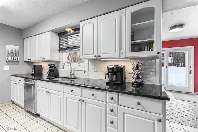 kitchen with glass insert cabinets, stainless steel dishwasher, white cabinetry, and a sink