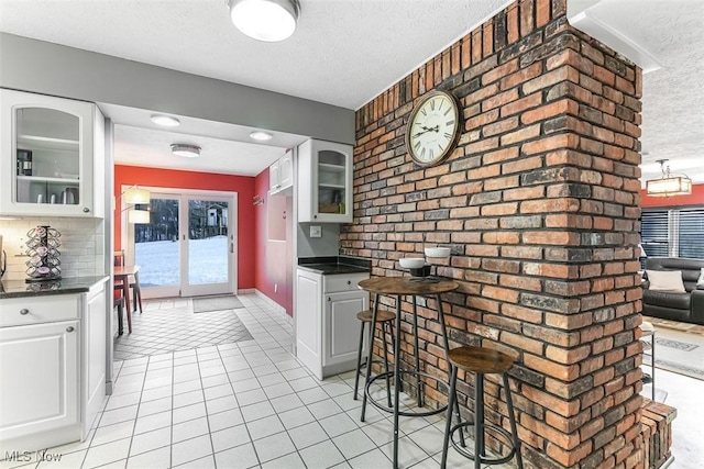 kitchen featuring glass insert cabinets, dark countertops, white cabinets, and a textured ceiling