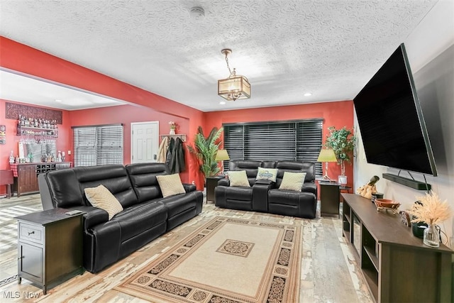 living area featuring a textured ceiling, recessed lighting, light wood-style floors, a bar, and an inviting chandelier