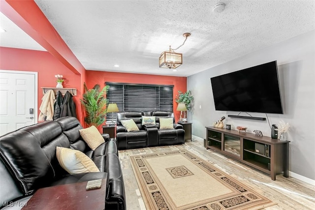 living area featuring a textured ceiling, a chandelier, wood finished floors, and baseboards