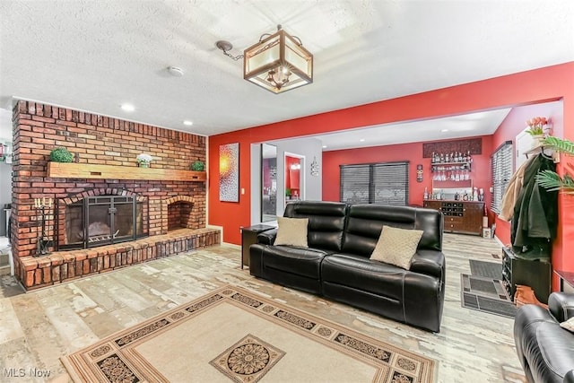 living area featuring a textured ceiling, a fireplace, wood finished floors, and recessed lighting