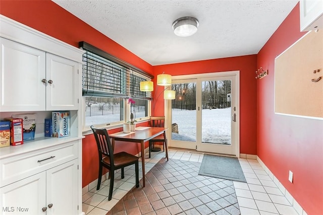 dining room featuring a textured ceiling, baseboards, and light tile patterned floors