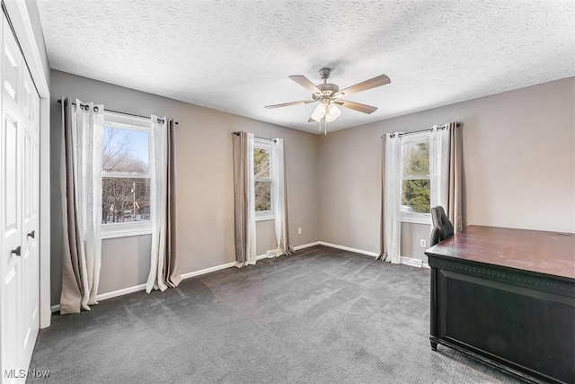 interior space with ceiling fan, a textured ceiling, dark carpet, and baseboards