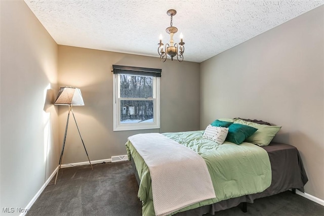 bedroom featuring baseboards, a textured ceiling, dark carpet, and an inviting chandelier