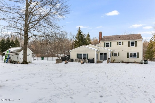 snow covered rear of property featuring a chimney