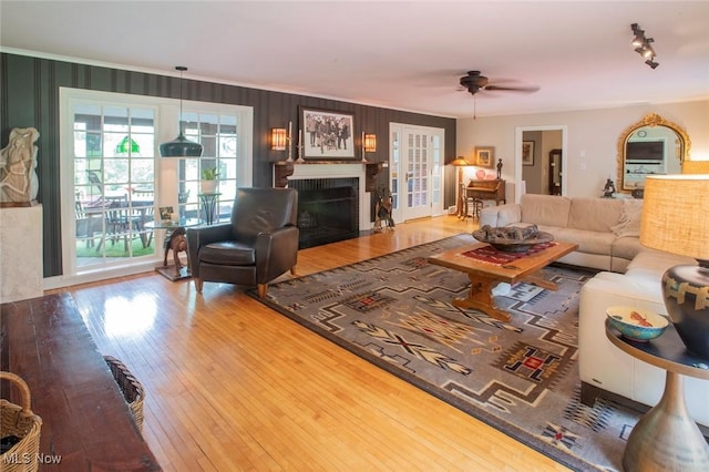 living room with crown molding, a fireplace, ceiling fan, and hardwood / wood-style floors