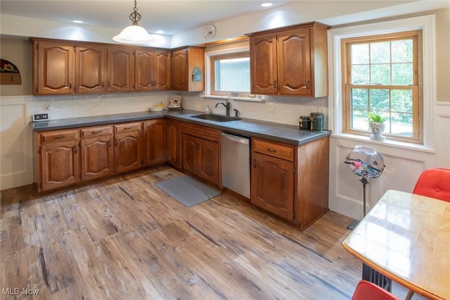 kitchen with light wood-type flooring, a sink, brown cabinetry, and stainless steel dishwasher