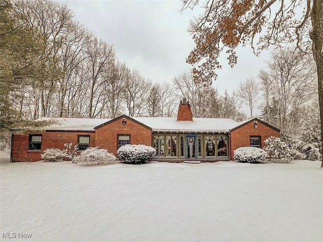 ranch-style house featuring brick siding and a chimney