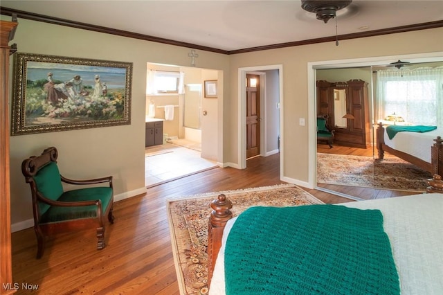 bedroom with ornamental molding, a closet, wood finished floors, and baseboards