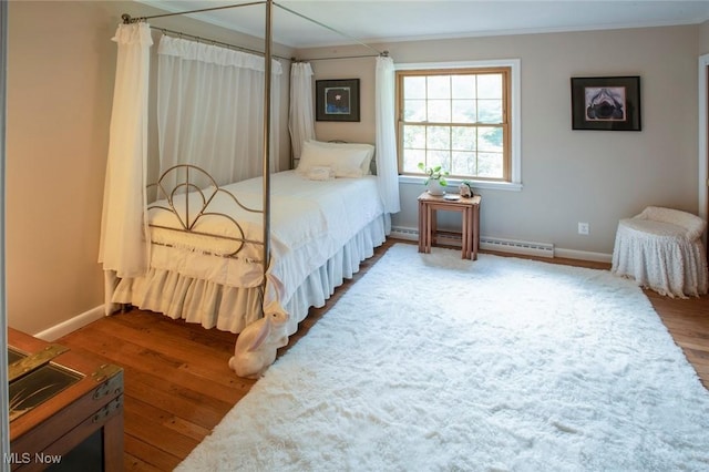 bedroom featuring a baseboard radiator, crown molding, baseboards, and wood finished floors