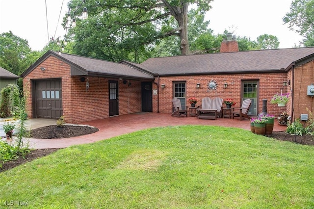 rear view of house with an attached garage, brick siding, a yard, a chimney, and a patio area