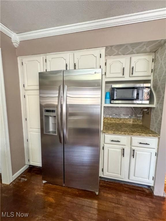 kitchen featuring white cabinets, stone countertops, ornamental molding, and stainless steel appliances