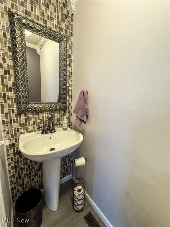 bathroom with tile walls, visible vents, decorative backsplash, wood finished floors, and baseboards