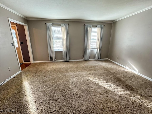 carpeted empty room featuring a wealth of natural light, crown molding, and baseboards