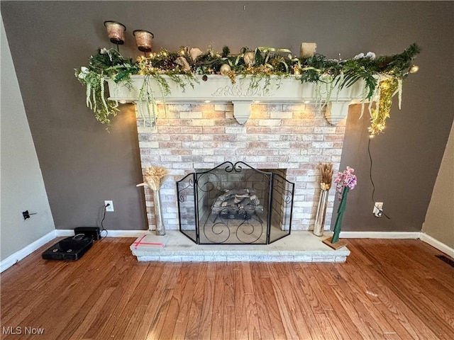 room details with a brick fireplace, baseboards, and wood finished floors