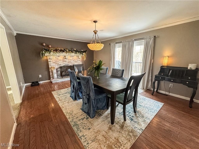 dining room with a fireplace with raised hearth, ornamental molding, dark wood finished floors, and baseboards