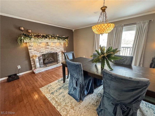 dining area featuring ornamental molding, wood-type flooring, a fireplace, and baseboards