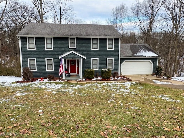 colonial home featuring a garage, driveway, and a yard