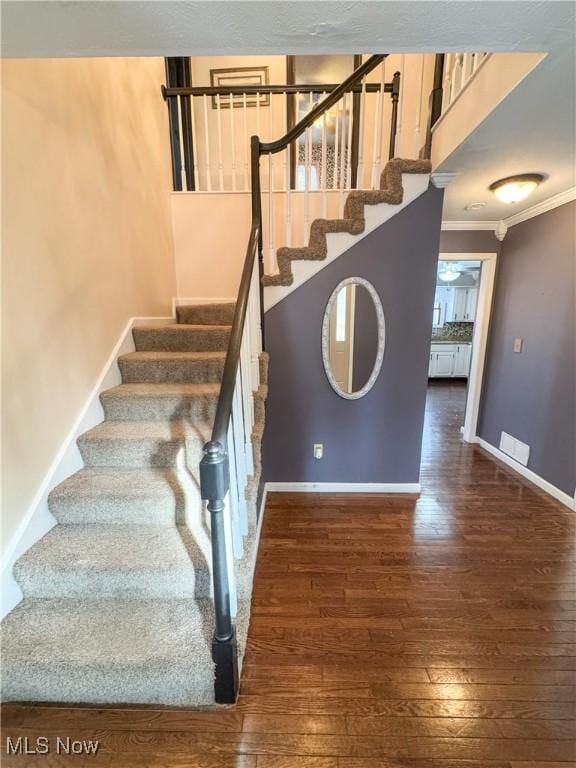 staircase featuring hardwood / wood-style flooring, baseboards, and crown molding