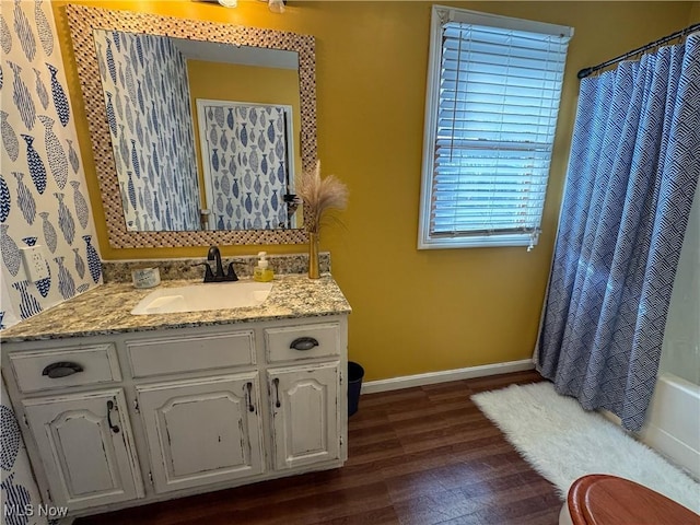 full bath with baseboards, toilet, shower / tub combo with curtain, wood finished floors, and vanity