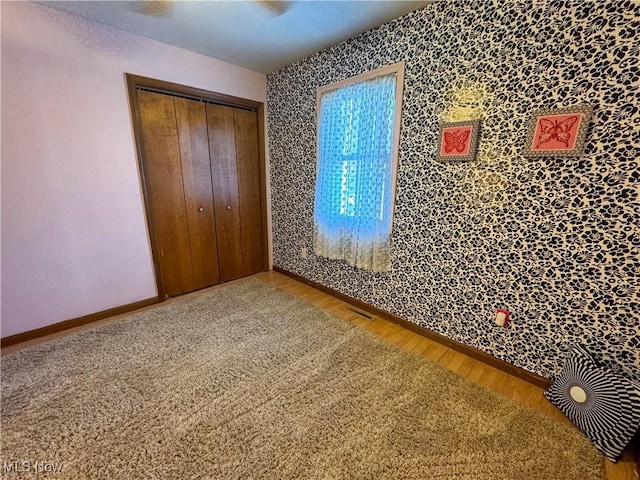 unfurnished bedroom featuring a closet, visible vents, baseboards, and wood finished floors