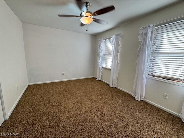 carpeted spare room featuring baseboards and a ceiling fan