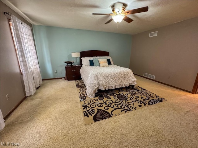 bedroom with a textured ceiling, ceiling fan, visible vents, and baseboards