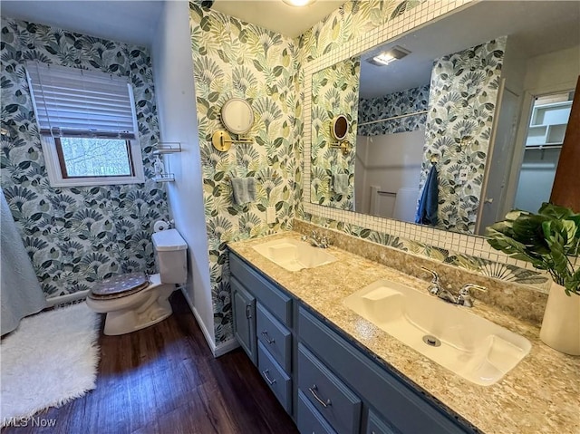 bathroom featuring double vanity, a sink, toilet, and wood finished floors