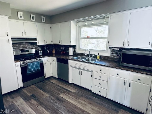 kitchen featuring under cabinet range hood, a sink, white cabinetry, appliances with stainless steel finishes, and dark countertops