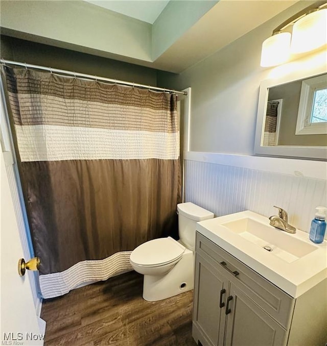 bathroom with wainscoting, toilet, wood finished floors, curtained shower, and vanity