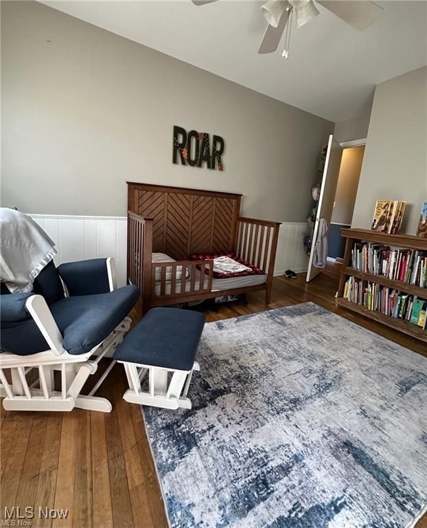 bedroom featuring wainscoting and dark wood finished floors