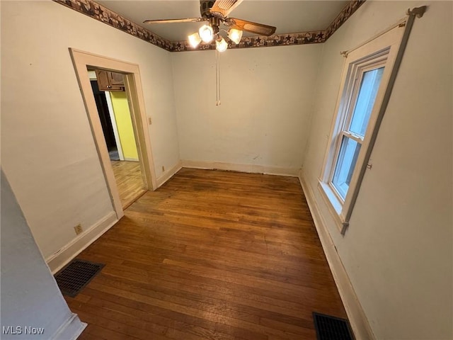 empty room featuring baseboards, visible vents, and hardwood / wood-style floors