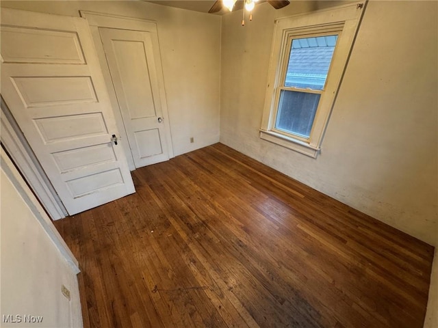 empty room with dark wood-type flooring and a ceiling fan