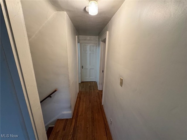 hall with dark wood-style floors and an upstairs landing