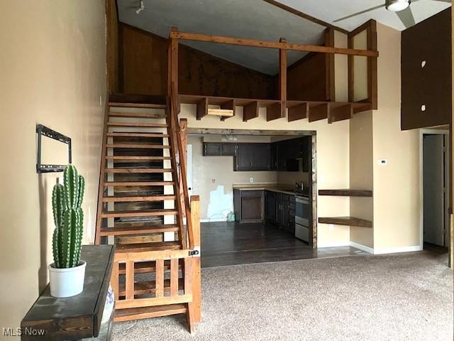 stairway with high vaulted ceiling, carpet, ceiling fan, and baseboards