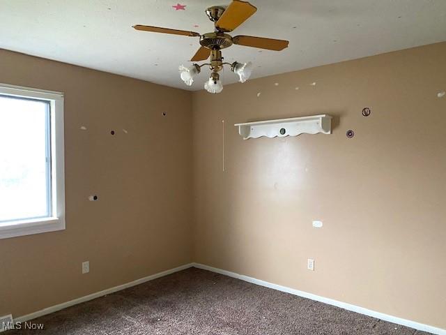 carpeted empty room featuring a ceiling fan and baseboards