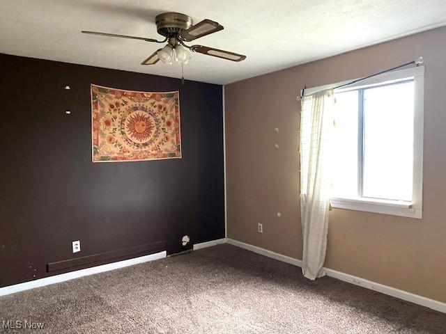 carpeted empty room featuring ceiling fan and baseboards