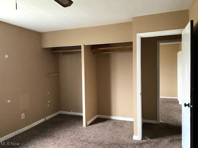 unfurnished bedroom featuring multiple closets, carpet, and baseboards