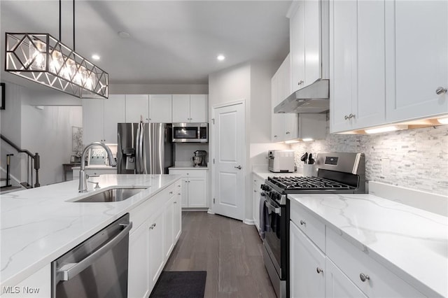 kitchen featuring white cabinets, decorative light fixtures, stainless steel appliances, under cabinet range hood, and a sink