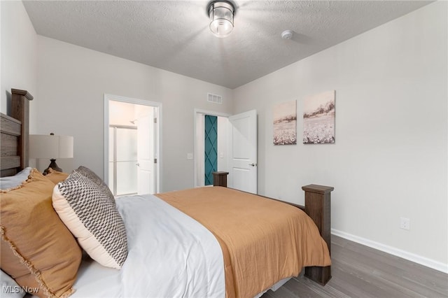 bedroom featuring a textured ceiling, dark wood-style flooring, visible vents, and baseboards