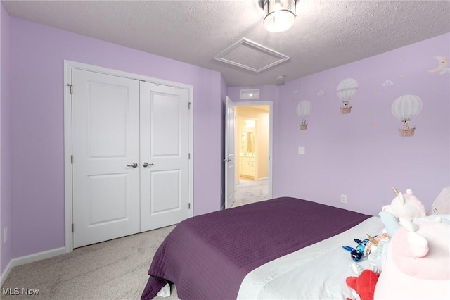 bedroom featuring attic access, baseboards, light colored carpet, a textured ceiling, and a closet